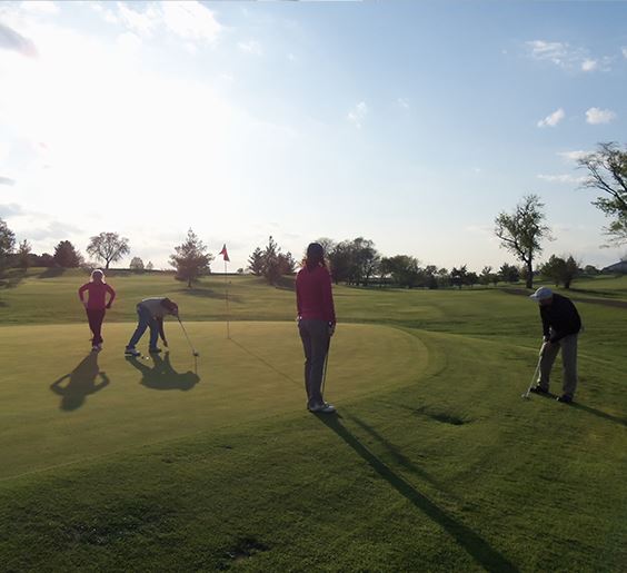 a photo of four people at on the putting green at Sugar Creek Golf Course