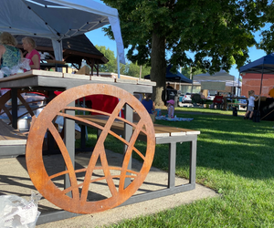 Metal Waukee City logo on side of a picnic table in Triangle Park