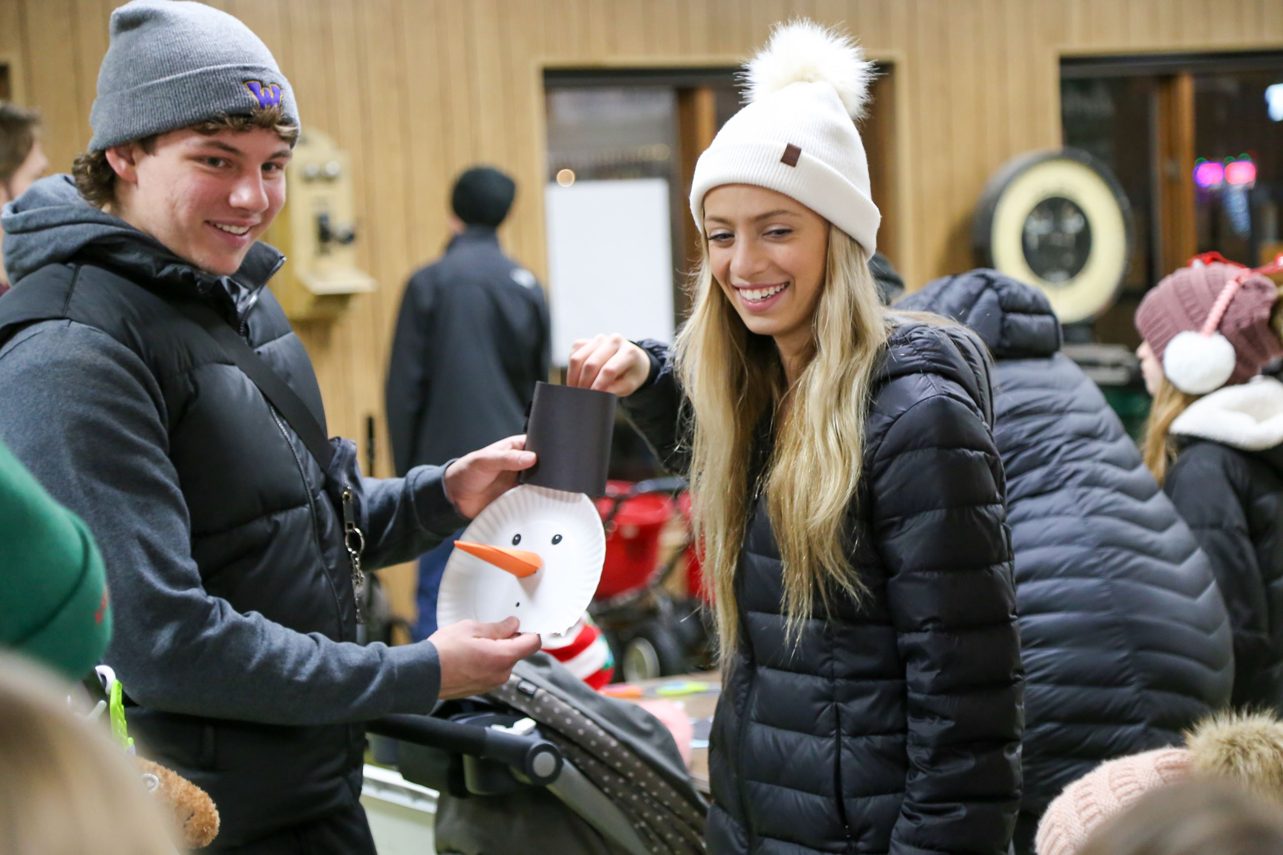 Young couple holding up a paper plate snowman craft