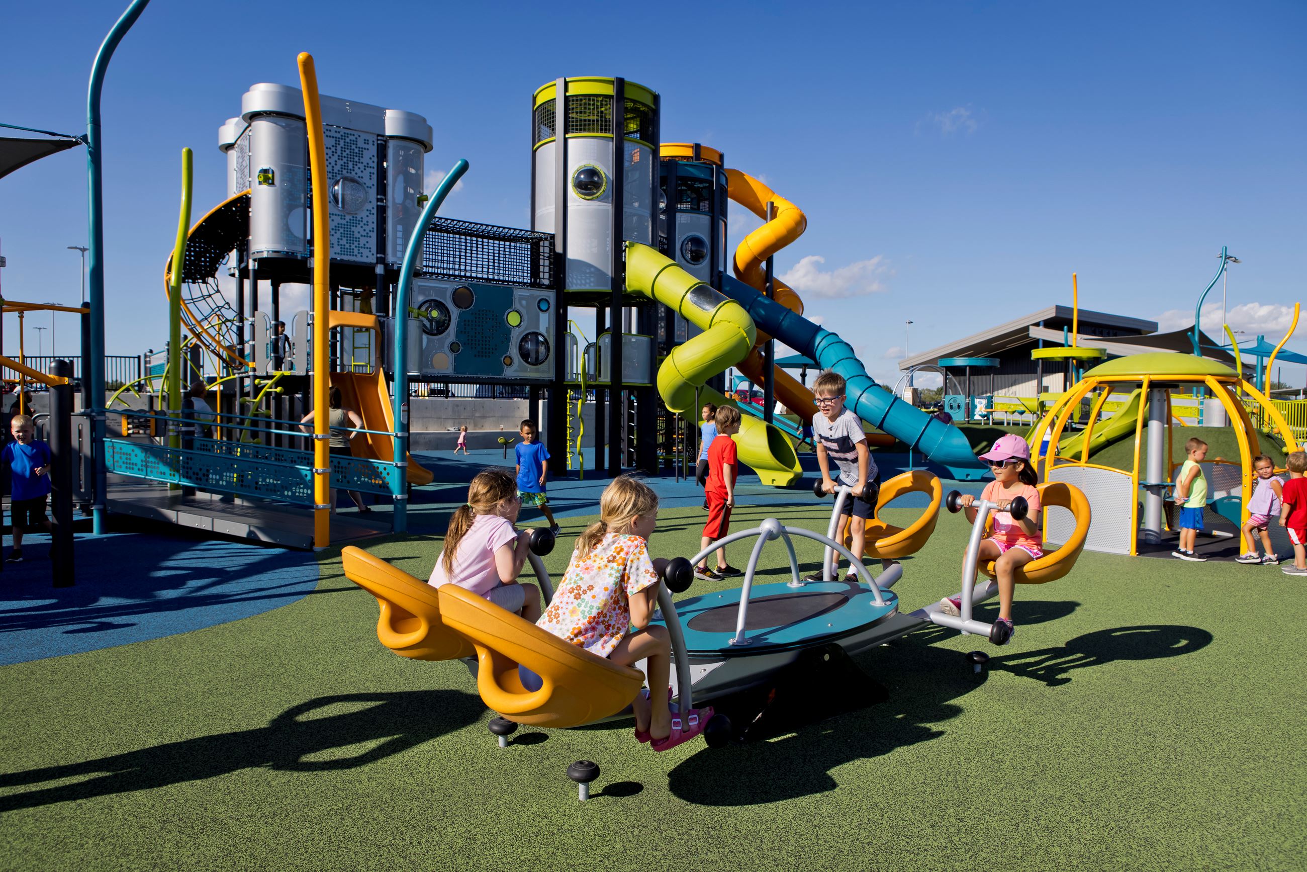 Four children sit in corner seats of the large seesaw