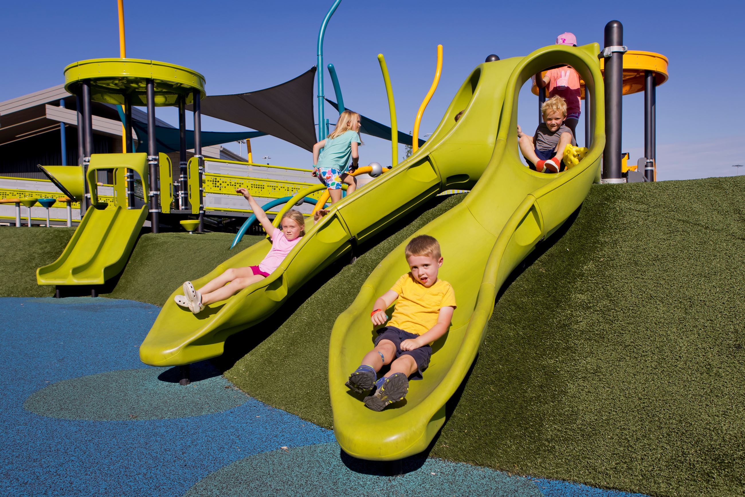 Children slide down two short slides designed for kids ages 2-5